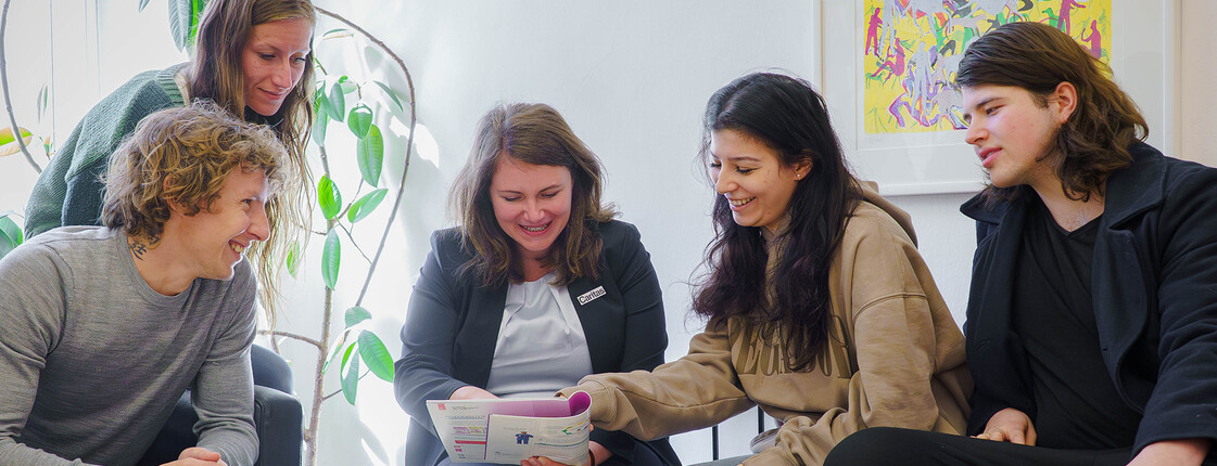 Gruppe von SOB-Studierenden sitzt gemeinsam mit der Schulleiterin Eva Daisenberger im Raum und bespricht gemeinsam Unterlagen der Ausbildung im Sozialbereich.