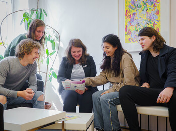 Gruppe von SOB-Studierenden sitzt gemeinsam mit der Schulleiterin Eva Daisenberger im Raum und bespricht gemeinsam Unterlagen der Ausbildung im Sozialbereich.